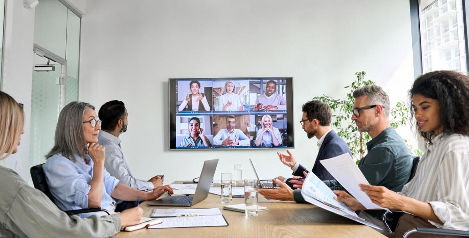 Board members and remote advisors reviewing a foreign company acquisition during a meeting