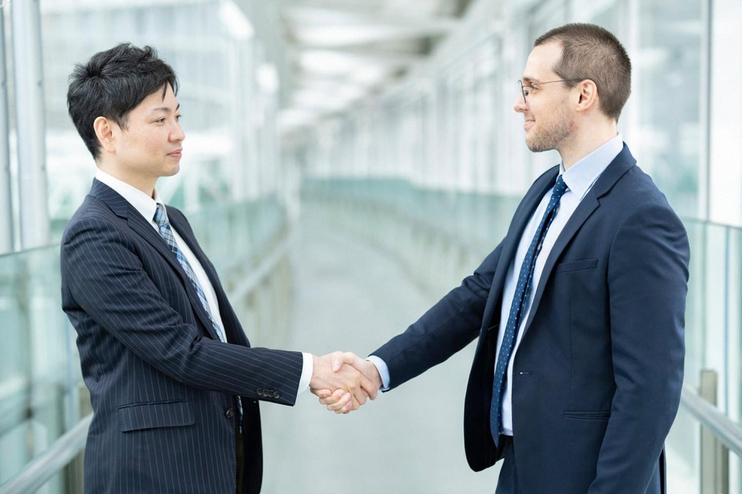 Two executives shaking hands after closing a cross-border share purchase deal